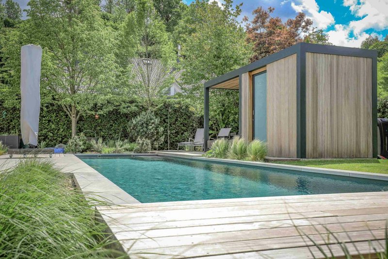 Modern backyard with a rectangular swimming pool, wooden decking, and a small pool house
