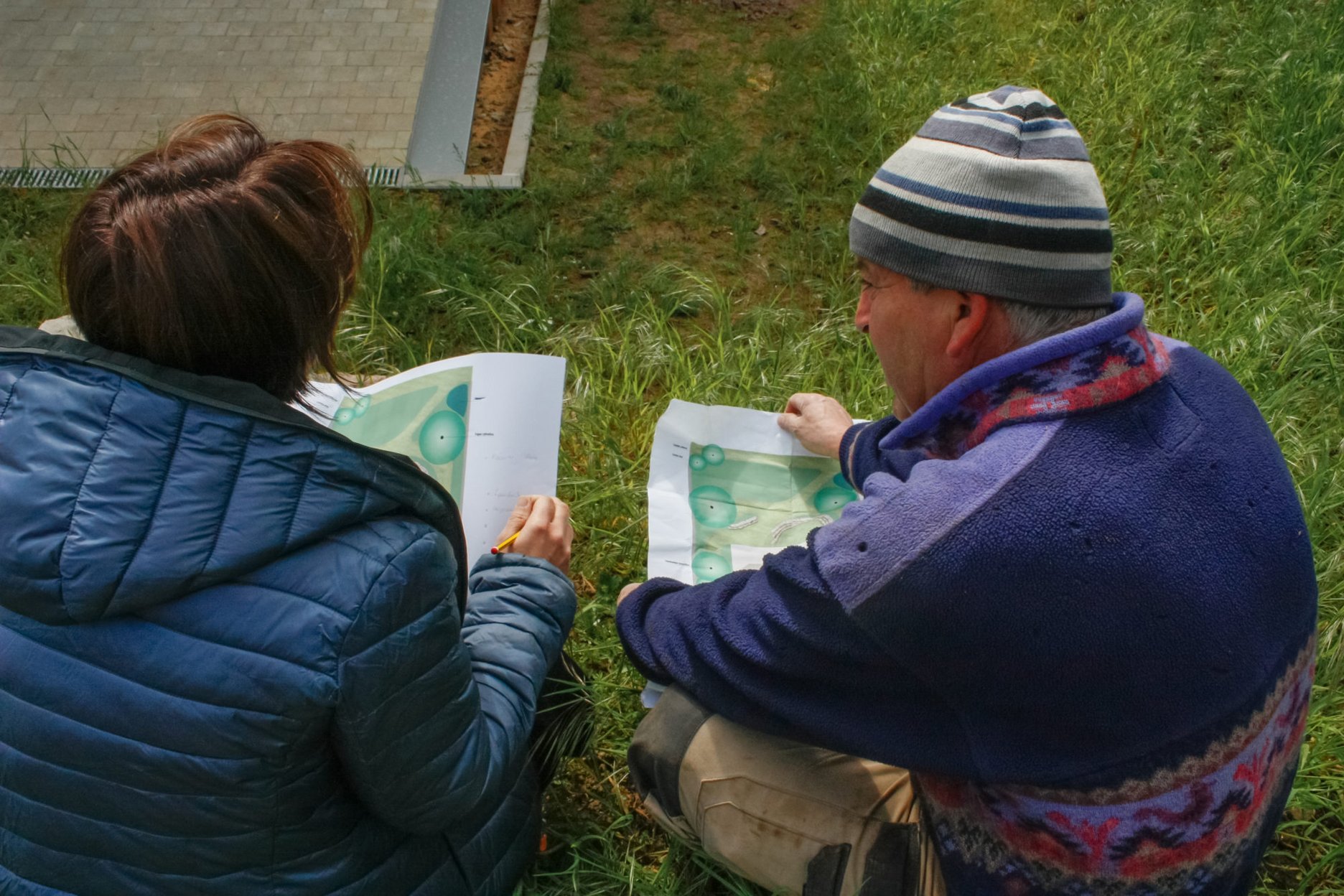 Zwei Landschaftsarchitekten im Freien betrachten gemeinsam Pläne auf Papier