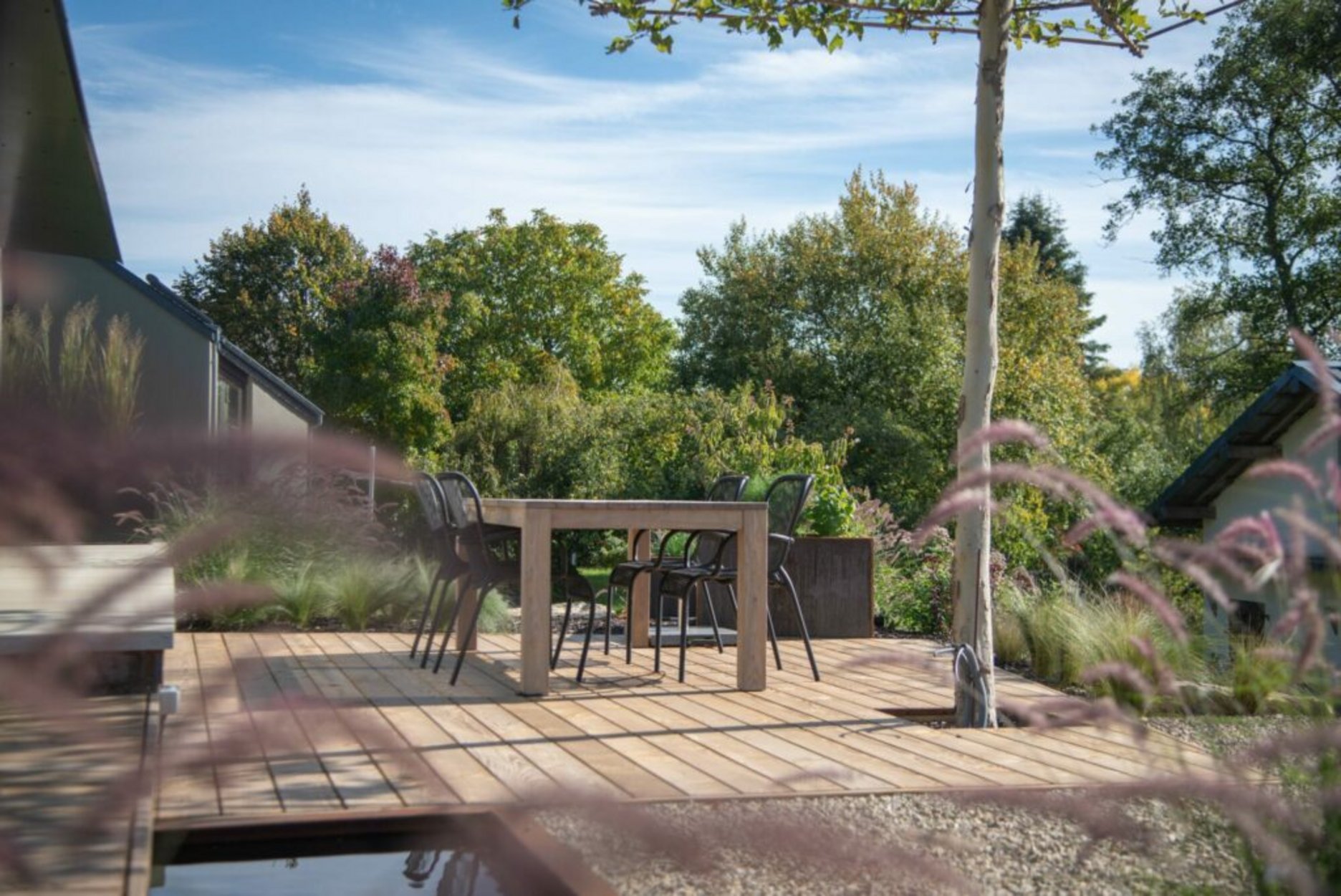Terrasse en bois avec table et chaises entourée de verdure